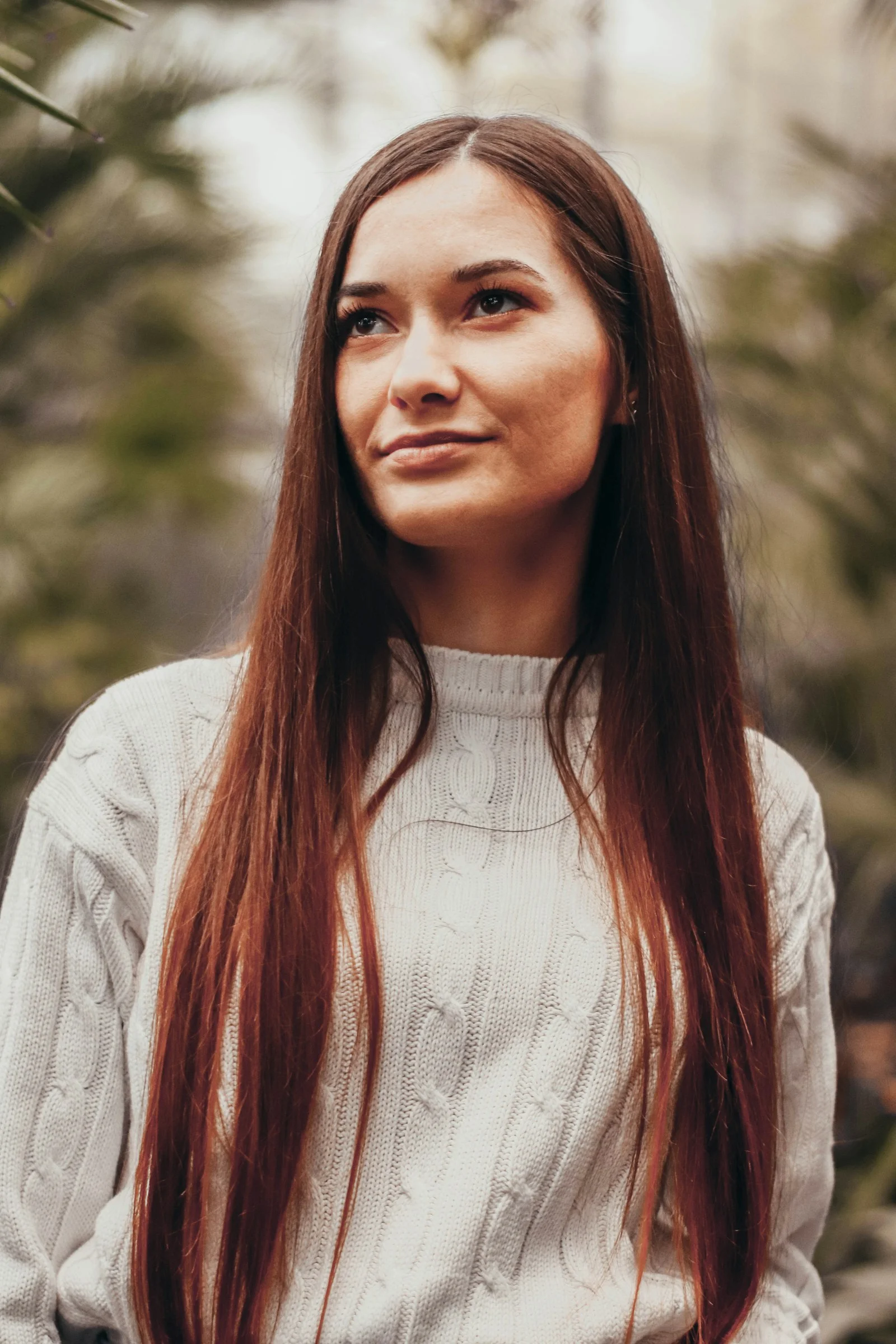a woman with long red hair standing in a forest