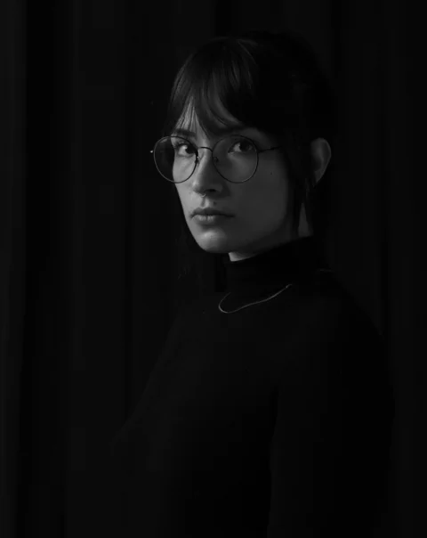 戴眼鏡、穿高領毛衣的女子的灰階照片