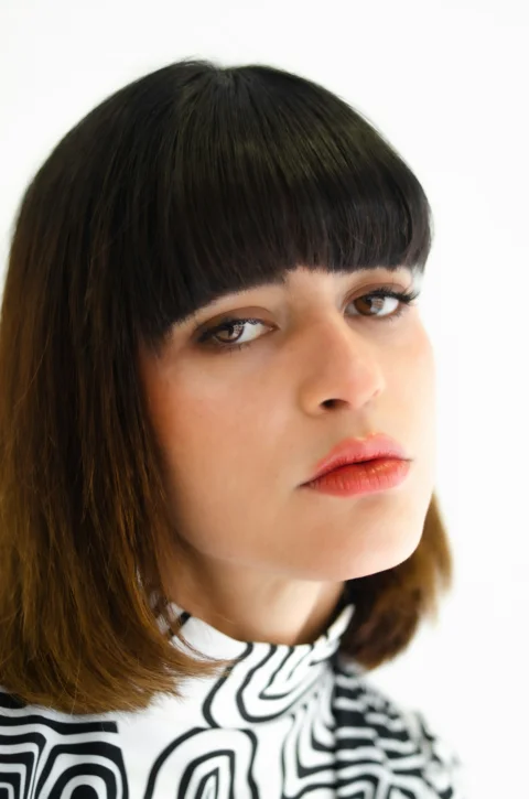 Close-up of a woman with dark bob haircut and bangs