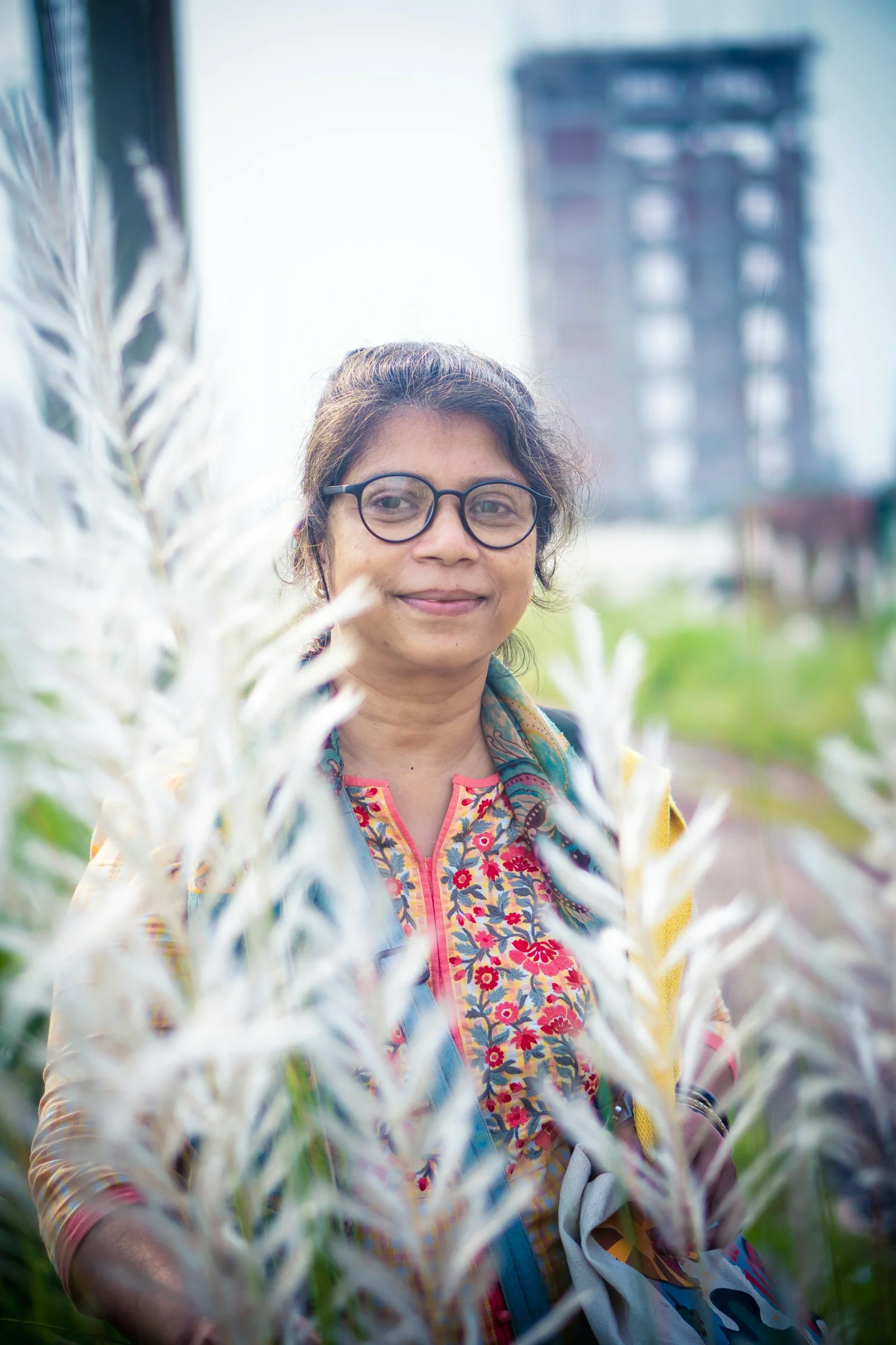 Woman with glasses smiles through white reeds