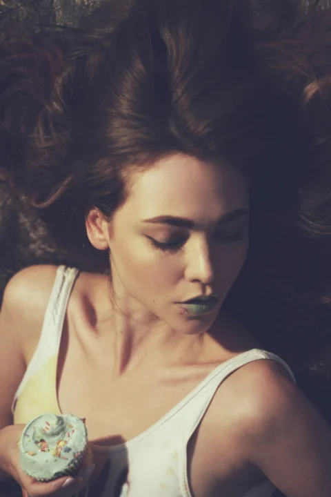 a woman with her hair blowing in the wind holding a donut