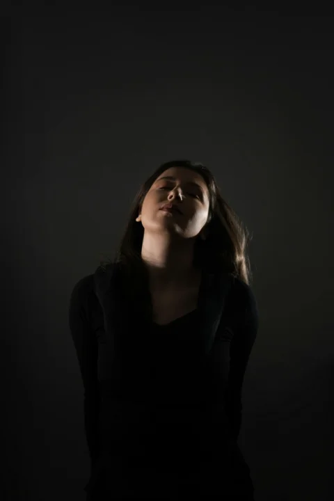 一位閉著眼睛站在黑暗中的女人