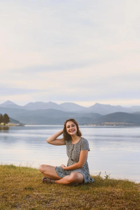 a woman sitting on the grass near a body of water