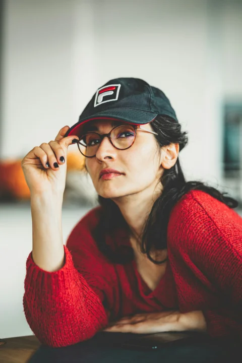 a woman wearing a hat and glasses sitting at a table
