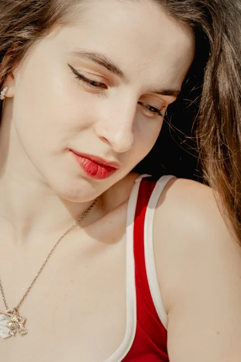 Young woman with dark hair and red lipstick looking down