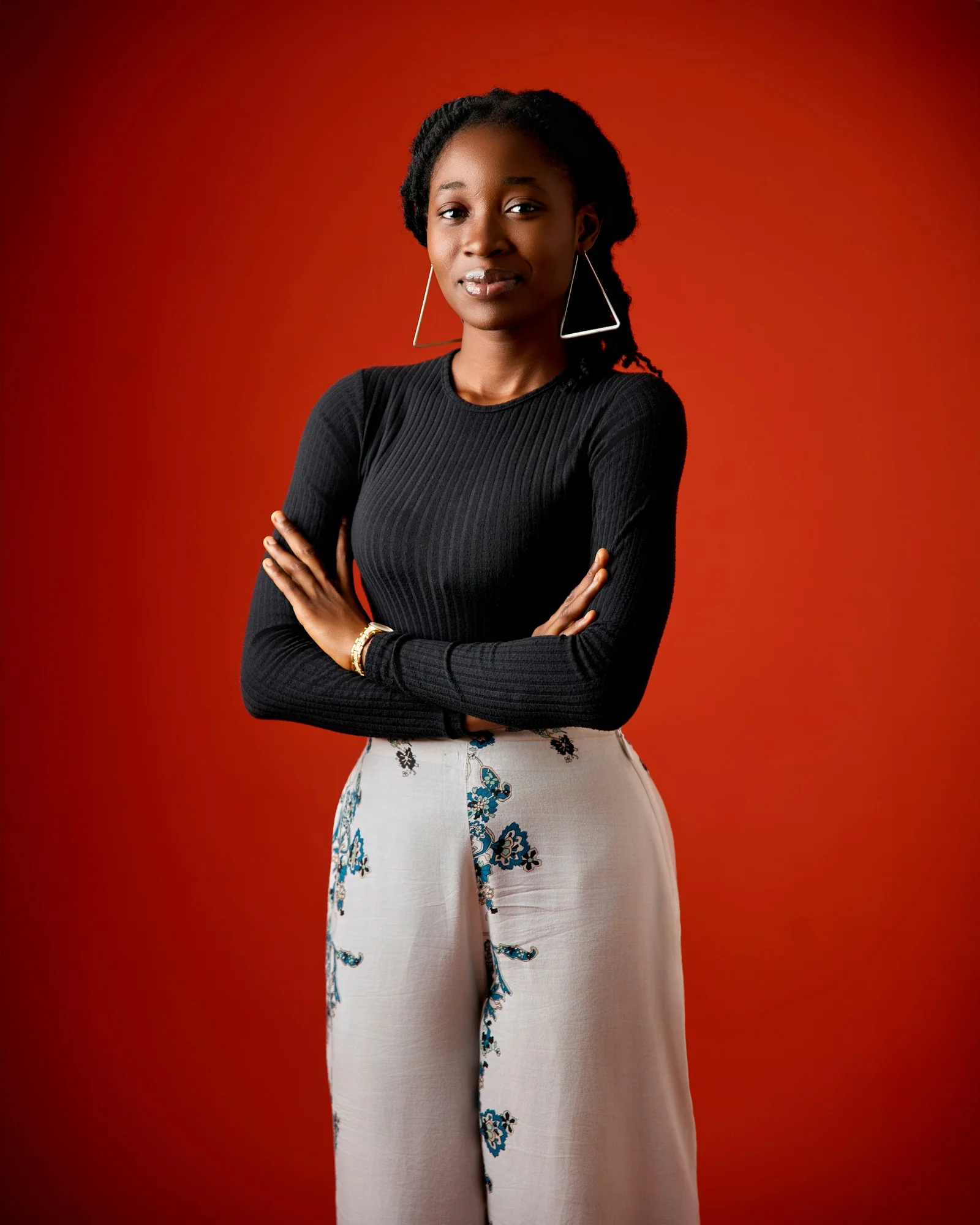 Young black woman with crossed arms on a red background