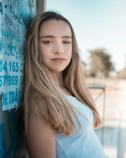 Young woman with long blonde hair leaning against wall