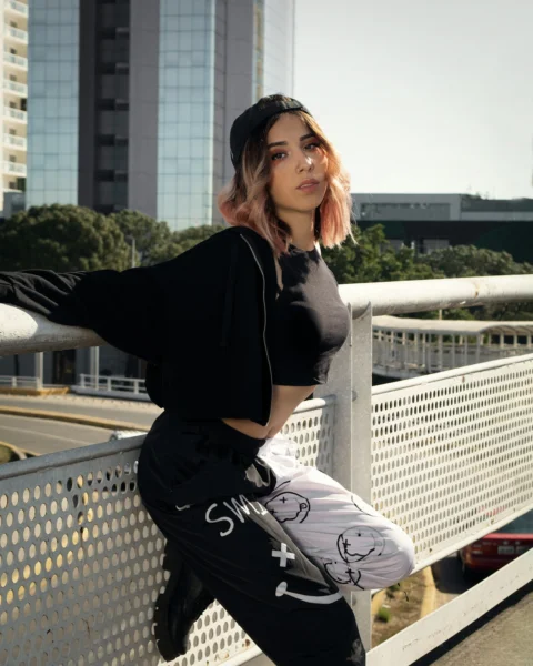 a woman leaning on a fence with her hand on her hip