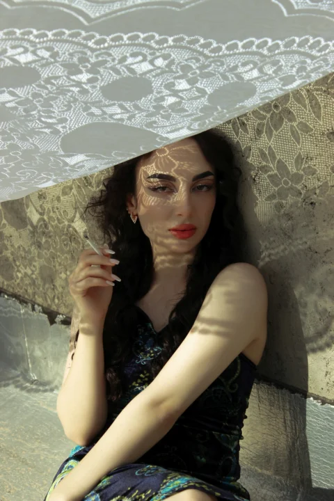 a woman sitting on the ground holding an umbrella