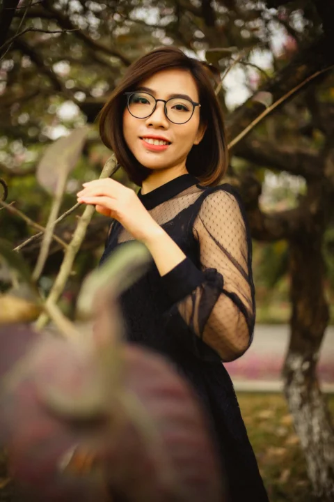 一位戴眼镜的女人站在树旁