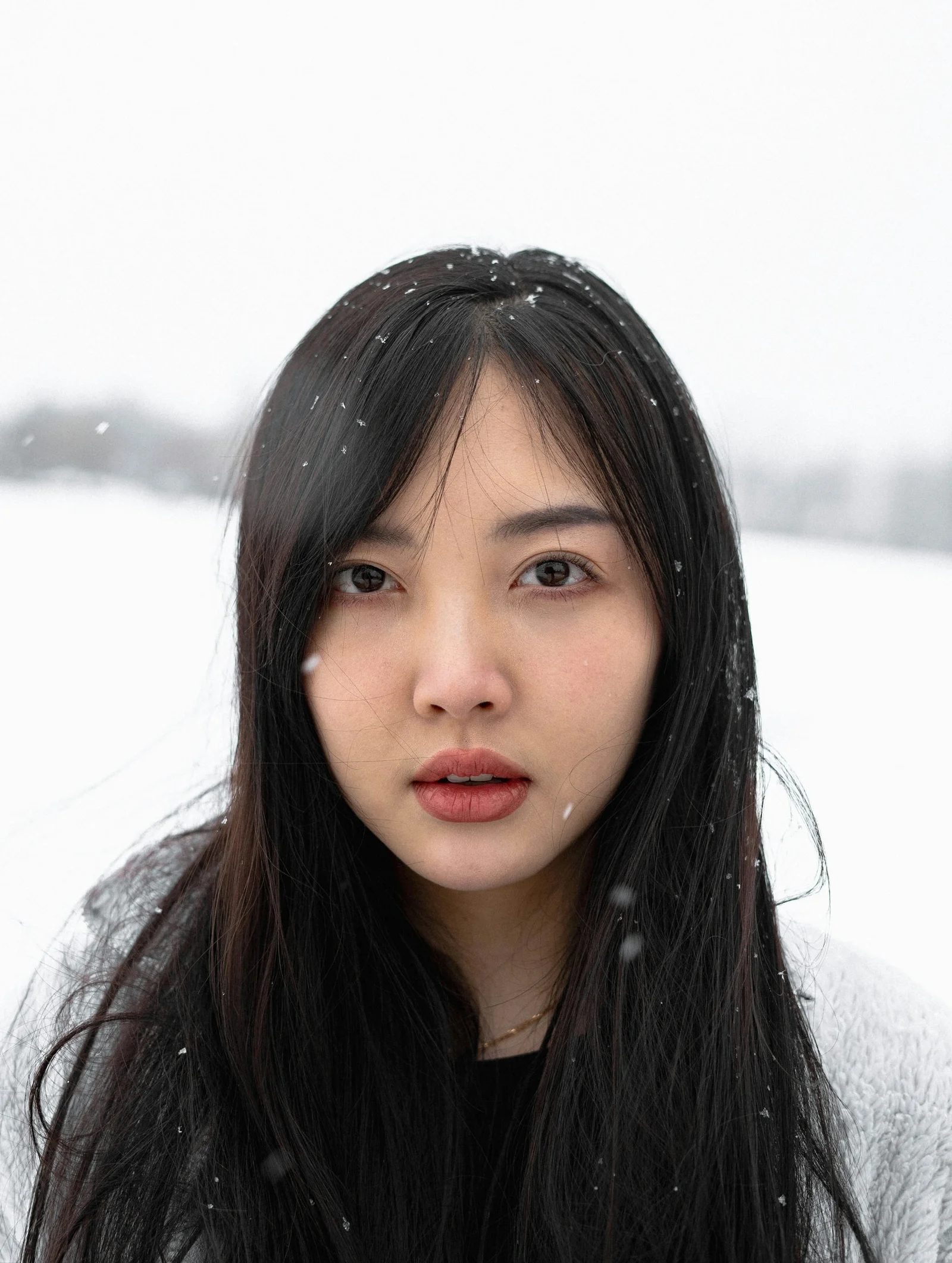 一个长黑发的女人站在雪中