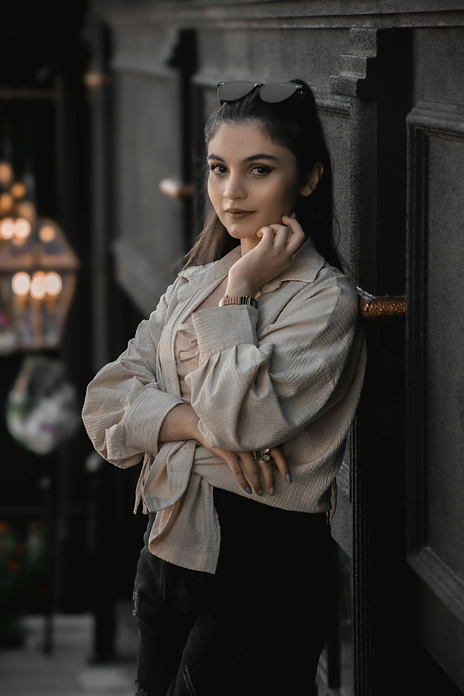 A woman leaning against a wall with her hand on her chin