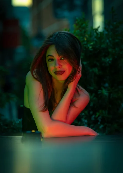 A woman with dark hair leaning on a table under green and red light