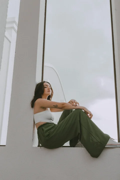 a woman sitting on a window sill looking out