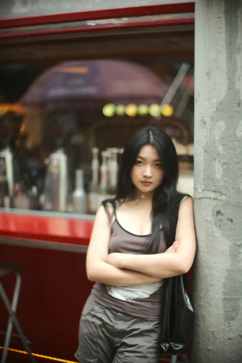 一位女士双臂交叉站在建筑物旁