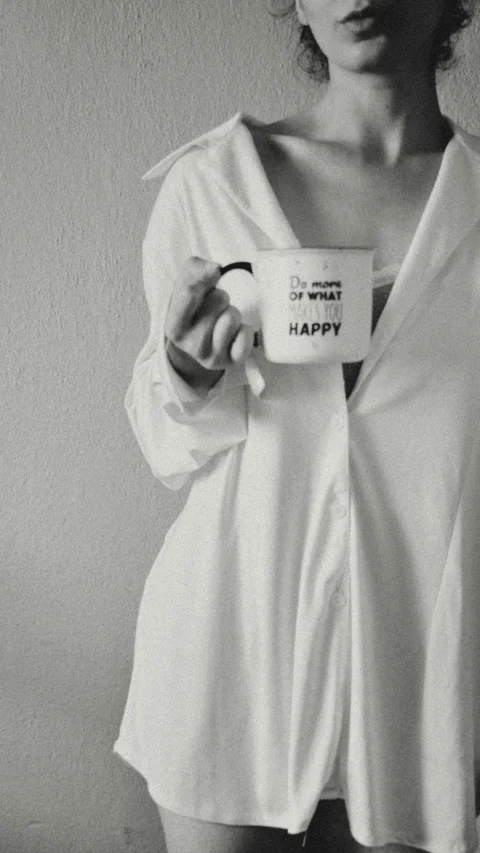 Woman in white shirt holding mug with inspirational quote