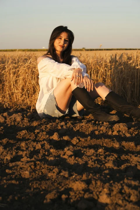 Woman sits in a field, enjoying golden hour