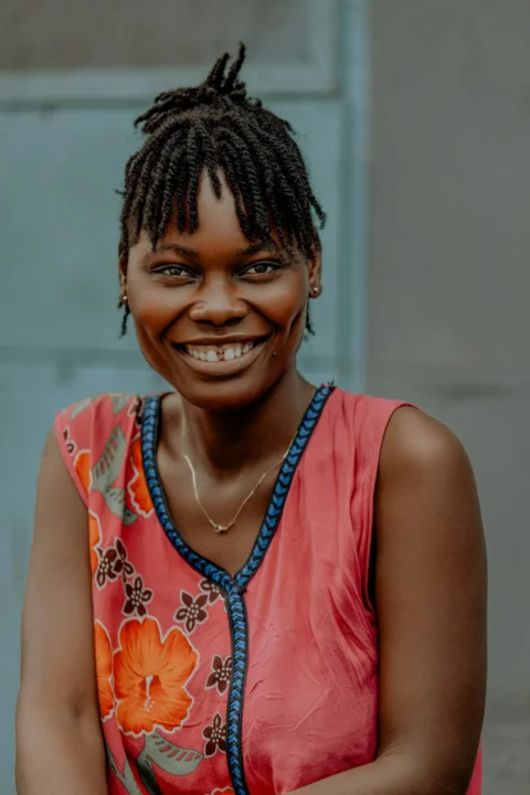 Smiling woman with braids and a vibrant patterned top