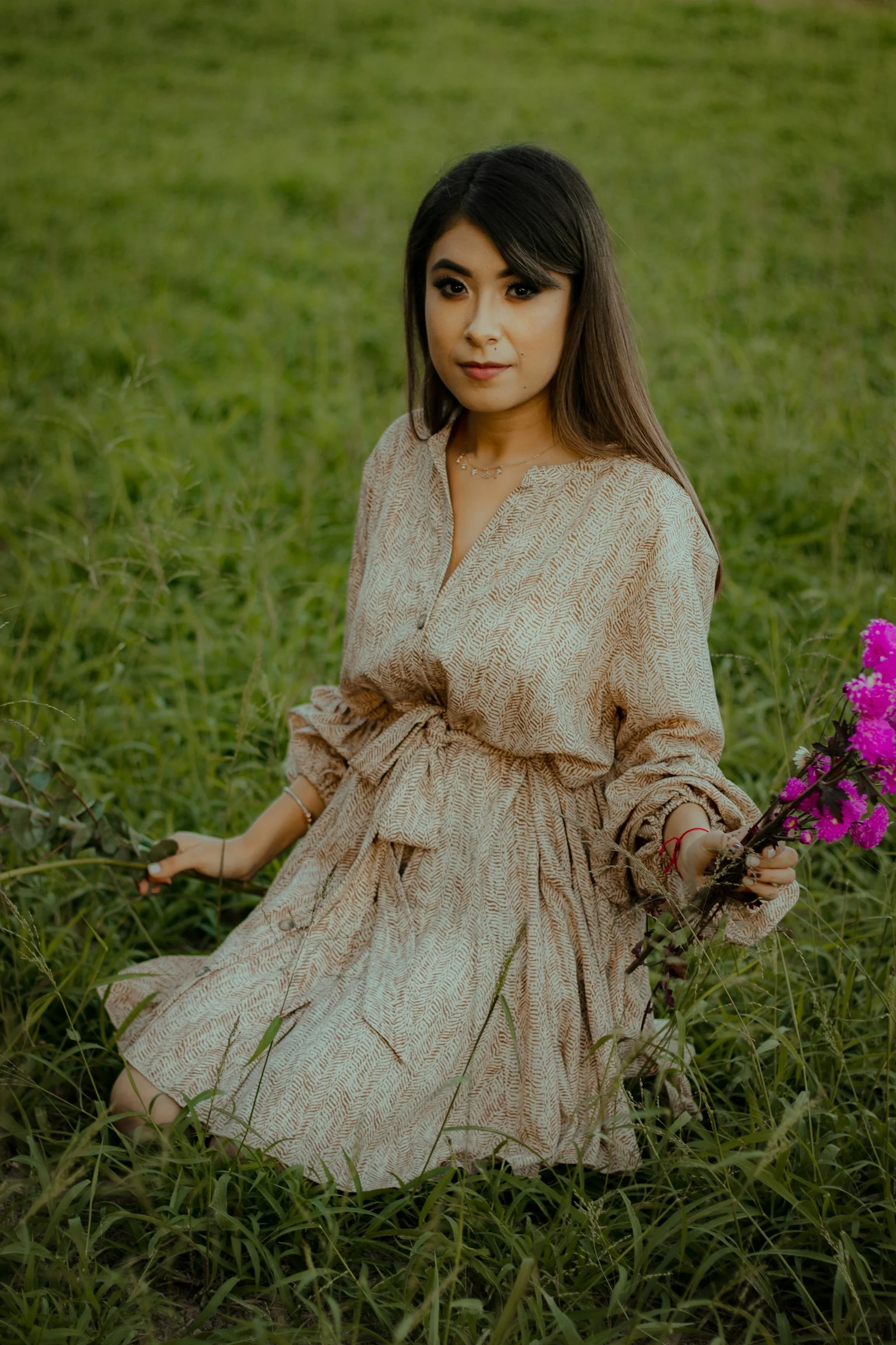 一位坐在田野中手拿紫色花朵的年轻女孩