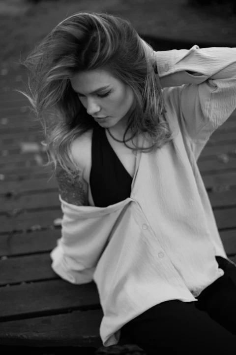 A black and white photo of a woman sitting on a bench