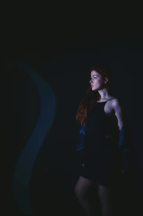 a woman in a black dress standing in the dark