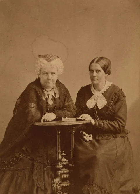 Two women seated at a table in vintage attire