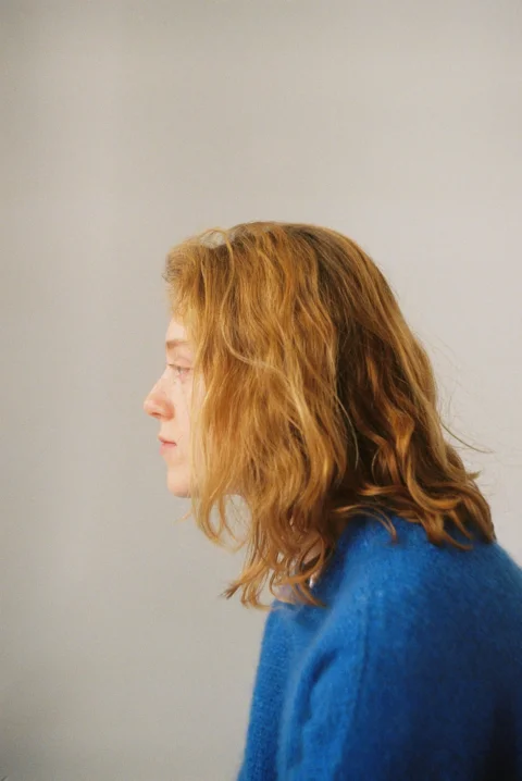 A woman in a blue sweater looking off into the distance
