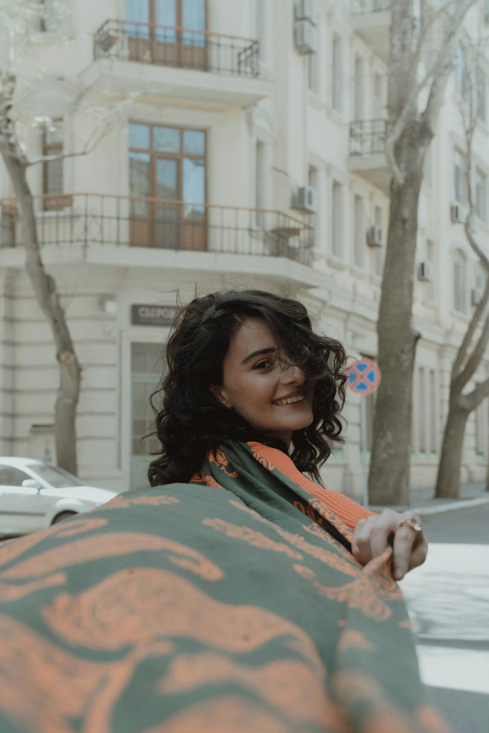 a woman standing on the street with a blanket on her back