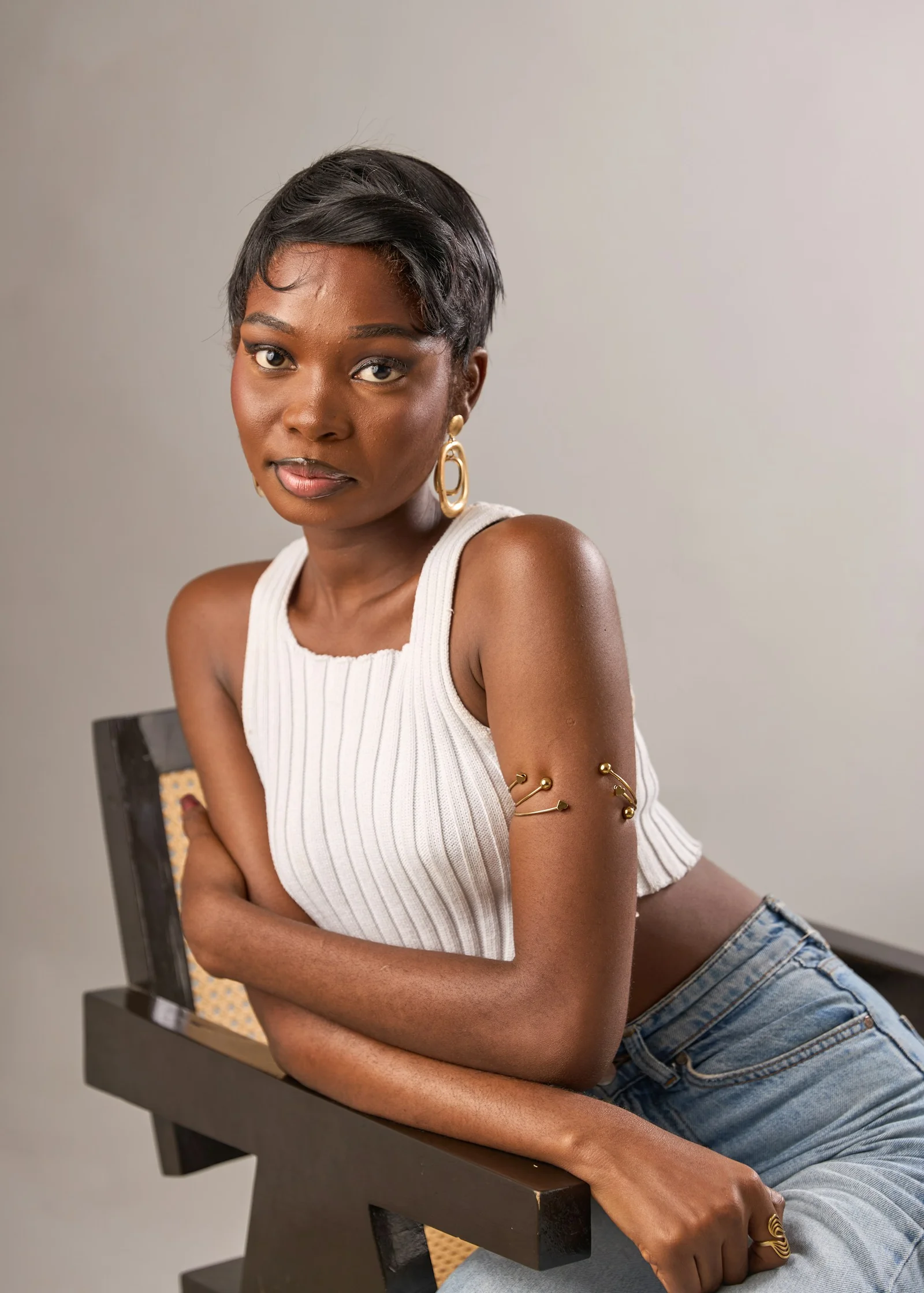 Young black woman in white ribbed top sitting on chair