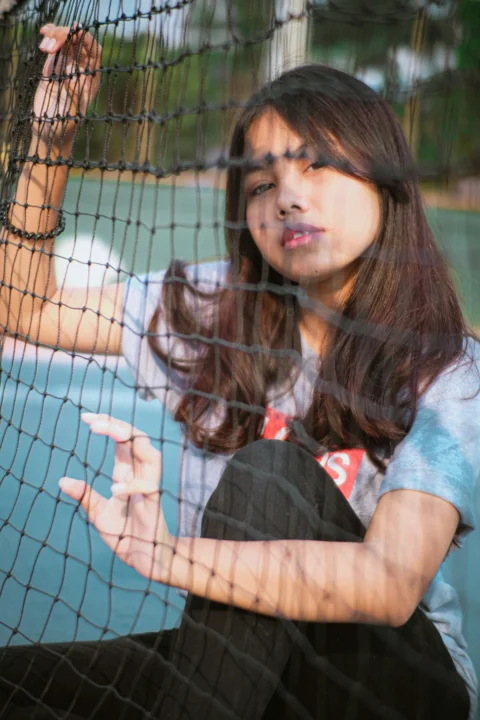 a woman sitting on the ground behind a net