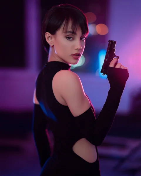 一名身穿黑色洋裝的女子手持一把槍