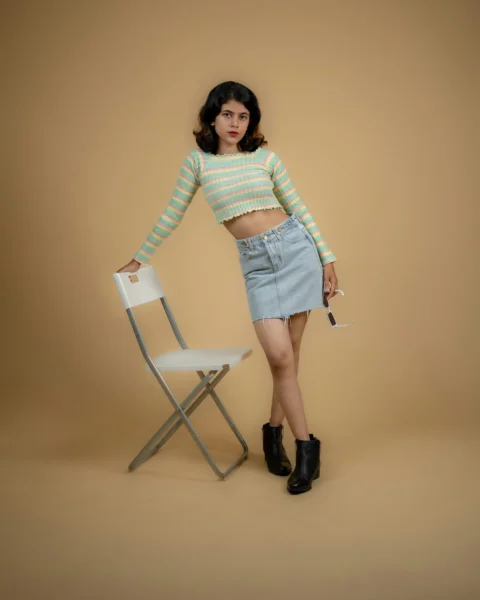 a woman standing next to a chair wearing a skirt