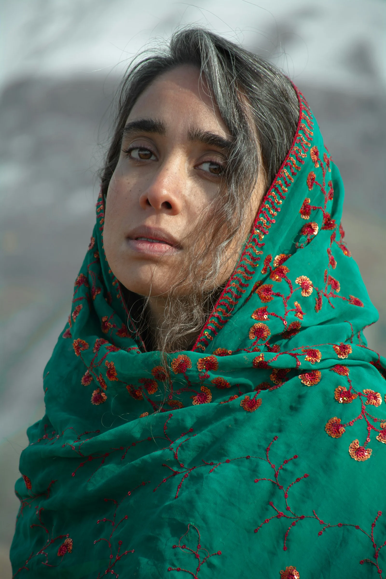 a woman wearing a green shawl with red flowers on it