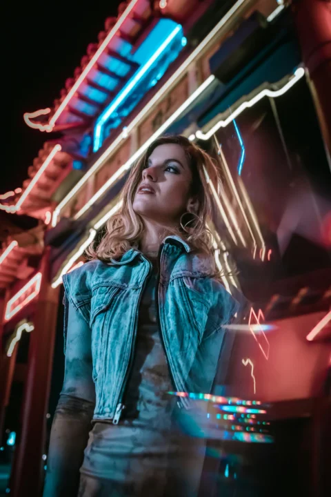 woman in blue denim jacket standing near glass window