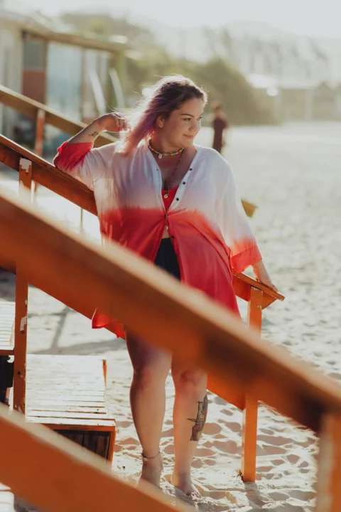 a woman in a red and white dress standing on a beach