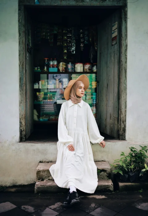 woman in white long sleeve dress standing near green plant