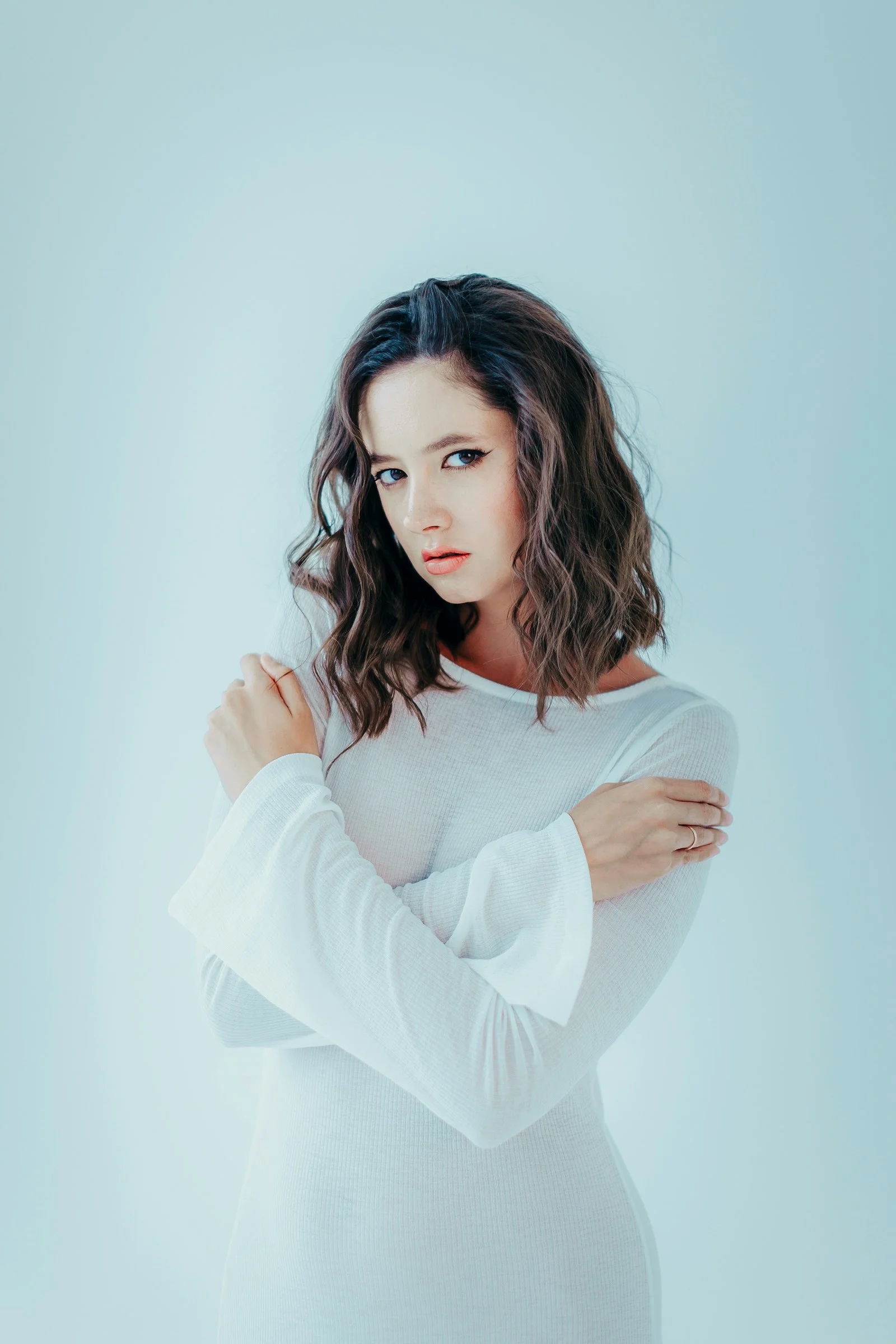 A woman in a white dress with arms crossed