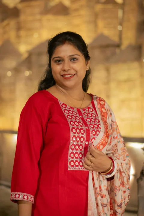 A smiling woman in a red outfit with patterned scarf