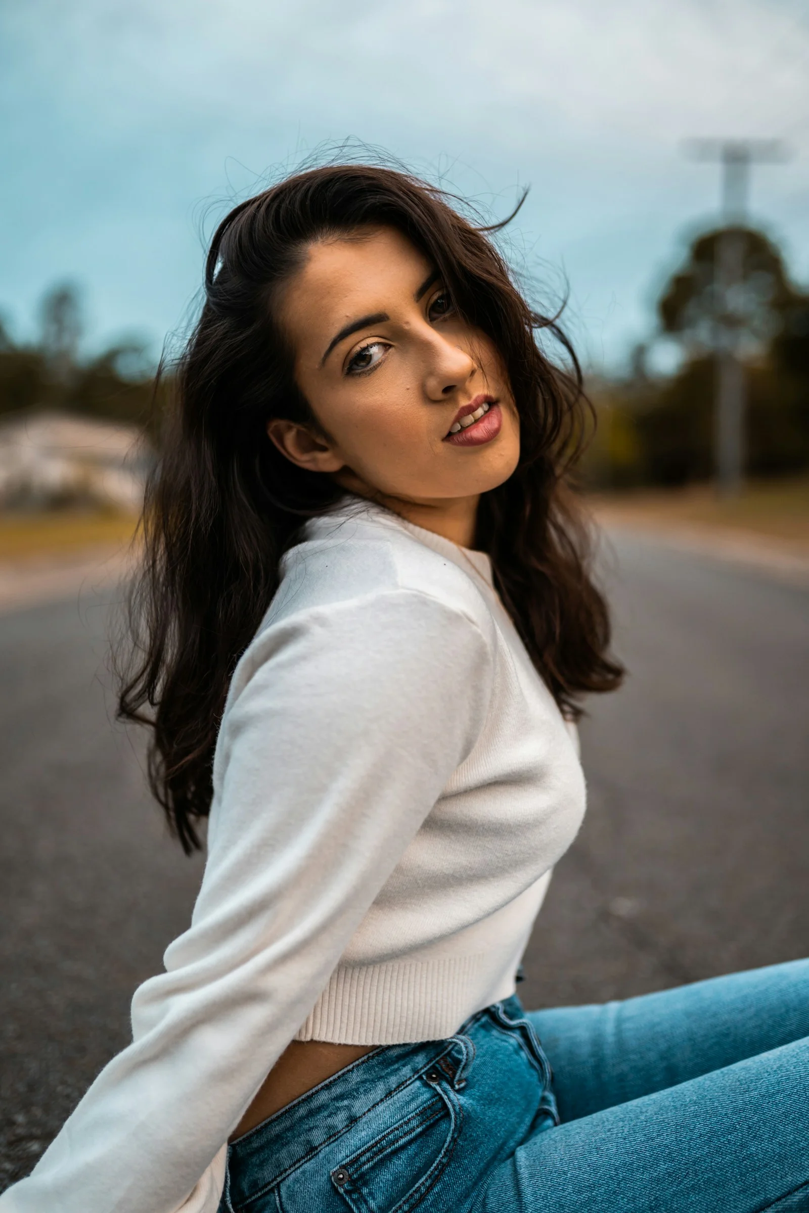 woman in white long sleeve shirt standing on road during daytime