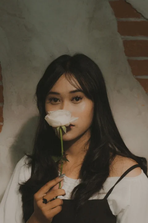 一名女性手中拿著一朵白玫瑰