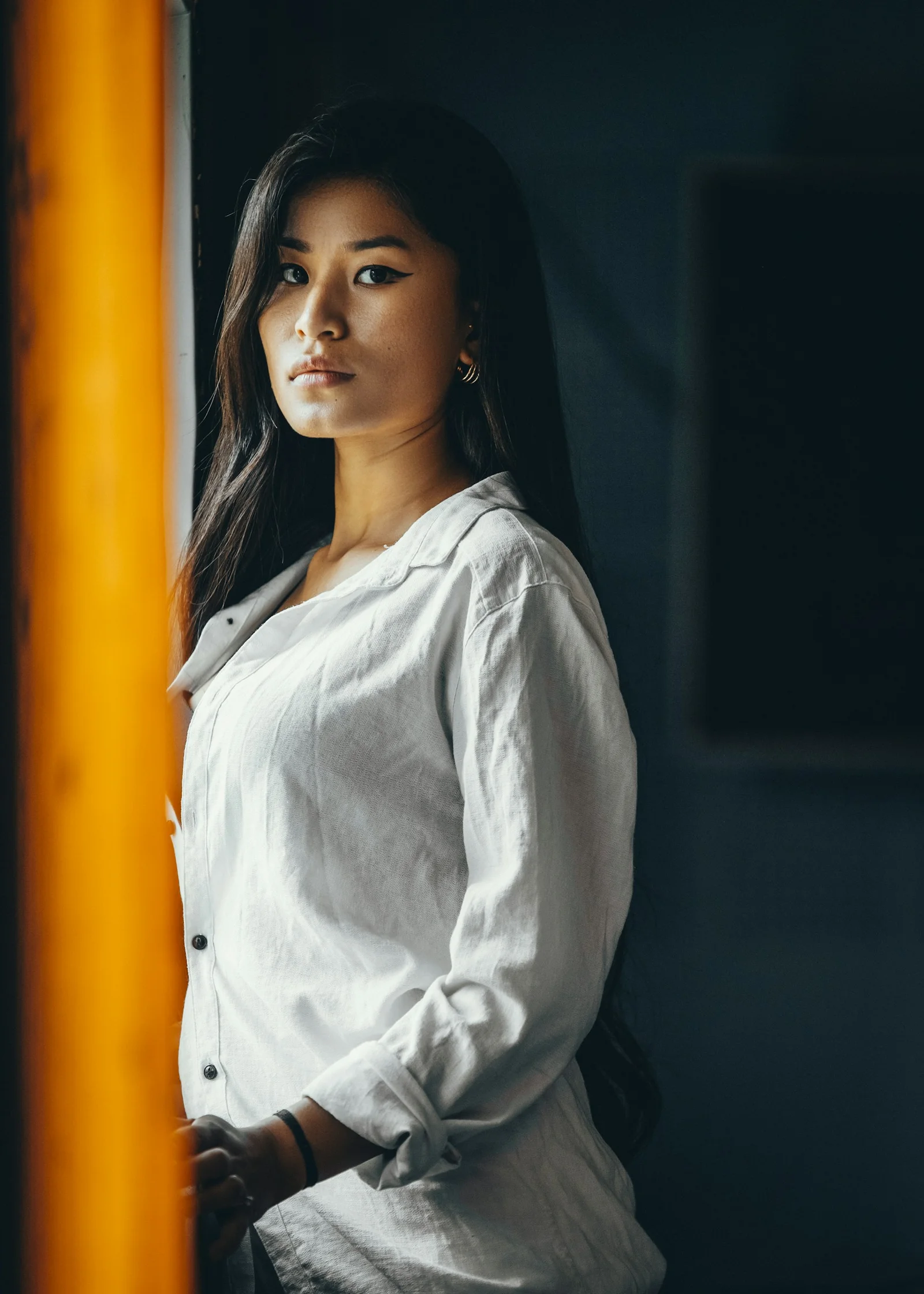 woman in white long sleeve shirt standing beside yellow metal pole