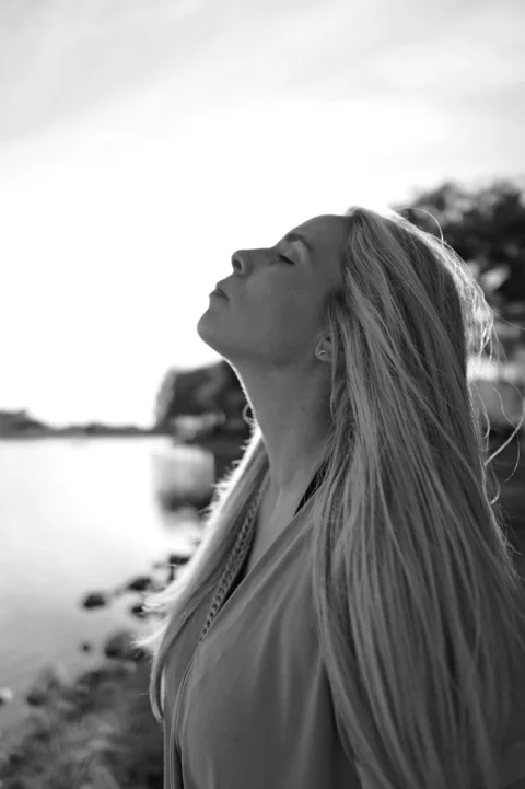 A woman with long hair standing by a body of water