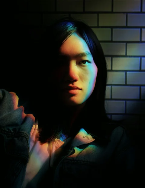 a woman with long hair standing in front of a brick wall