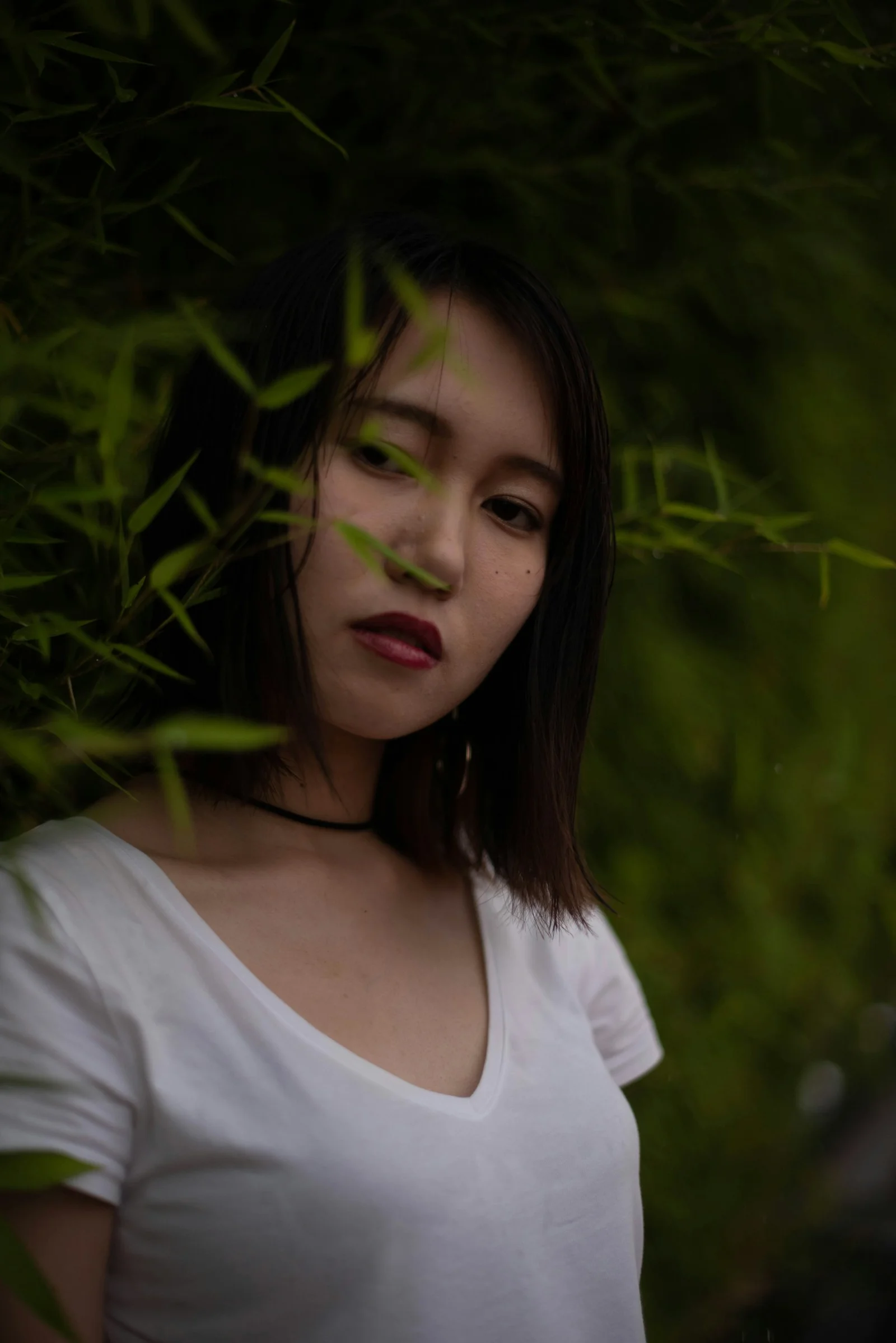 一位女人站在綠色灌木叢前