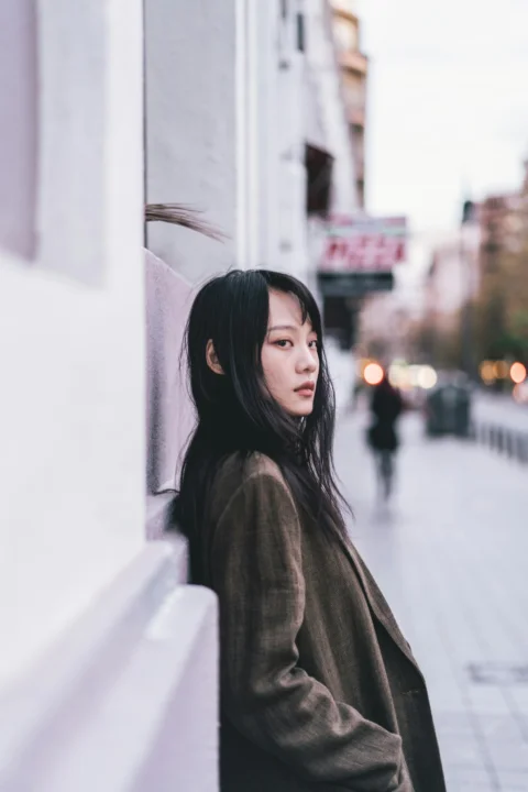 女子靠在路旁的建筑物上