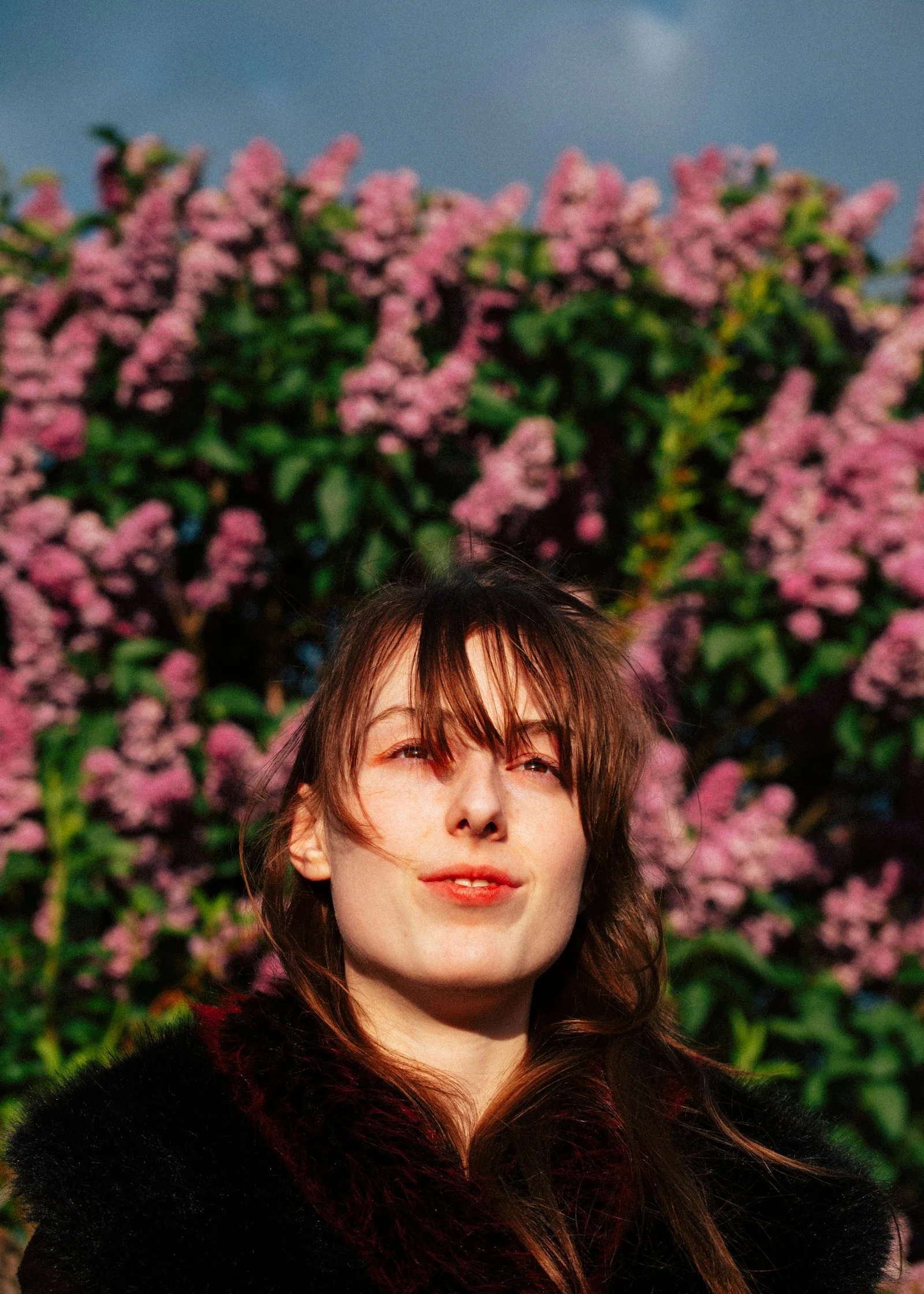 Young woman in front of blooming pink flowers
