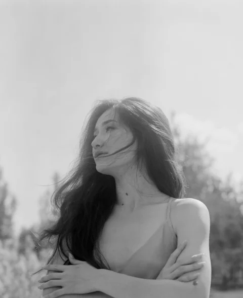 双臂交叉站在田野里的女人