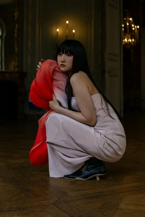 A woman kneeling on the floor holding a red pillow