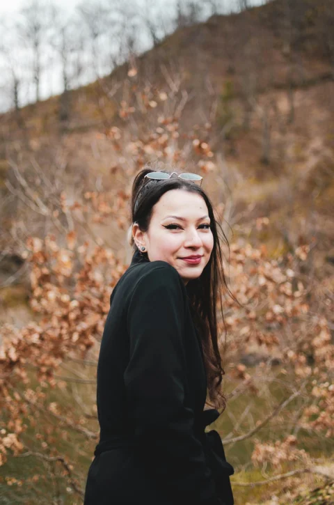 woman in black long sleeve shirt standing near brown trees during daytime