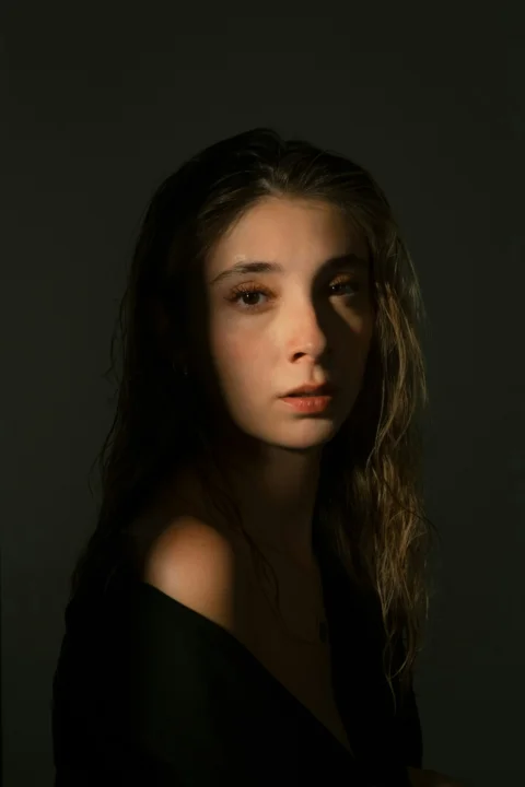 A young woman's face dramatically lit in shadow